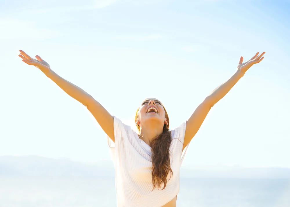 autism transition program | Woman smiling arms raised up to blue sky celebrating freedom