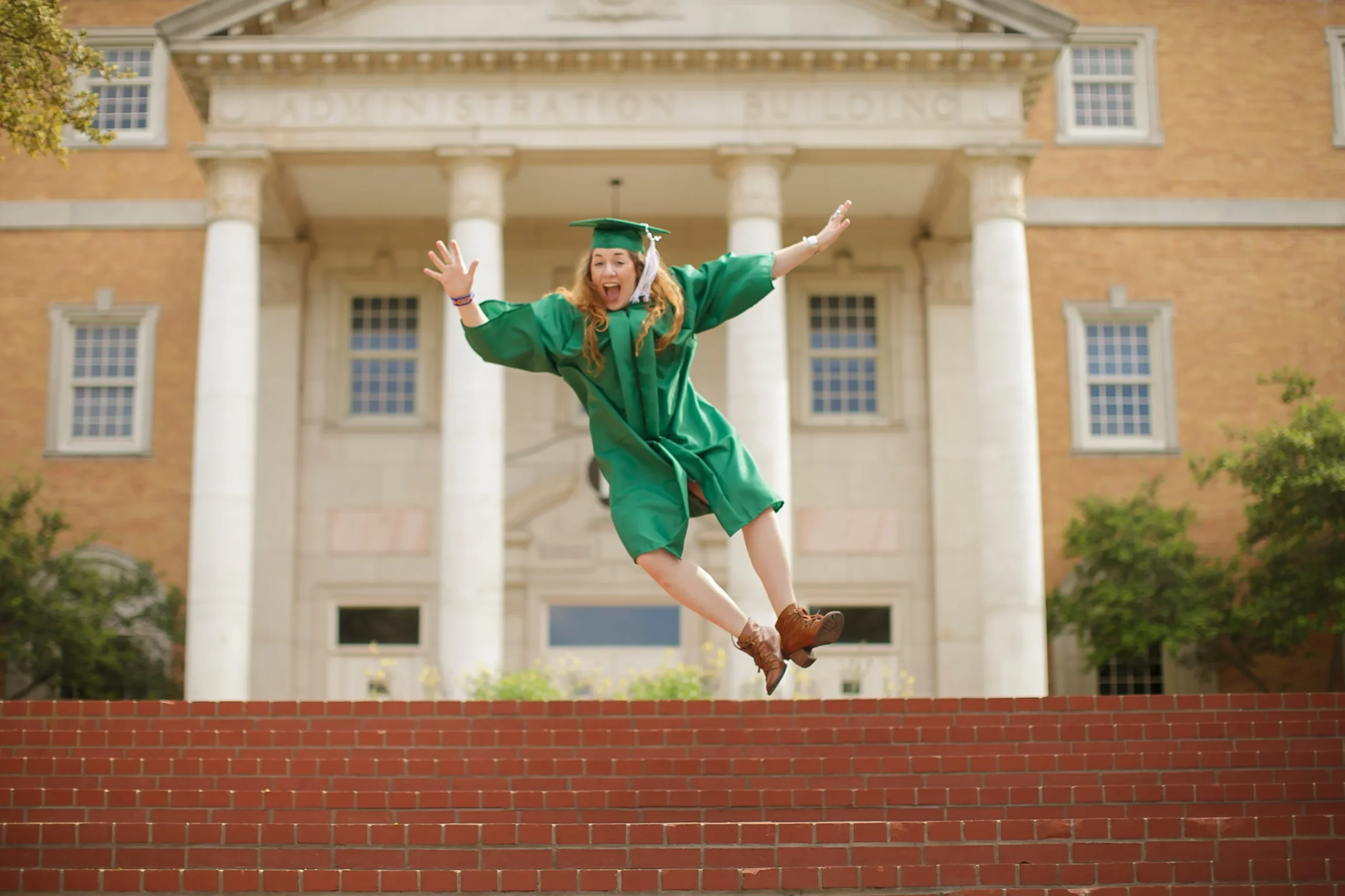 College Student with graduation gown jumping for joy